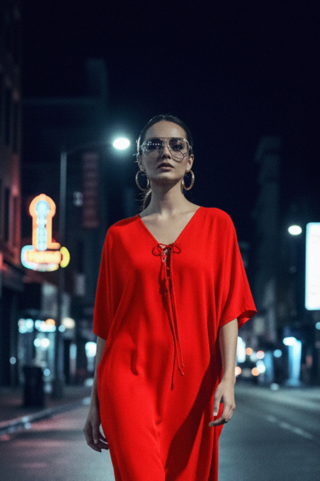Modern red midi dress with loose silhouette and front tassel tie, captured in an urban night-time fashion editorial.