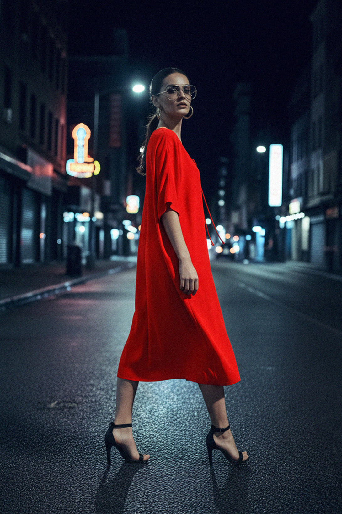 Fashion-forward red kaftan-style midi dress with relaxed fit and front tie detail, styled with heels and statement glasses.